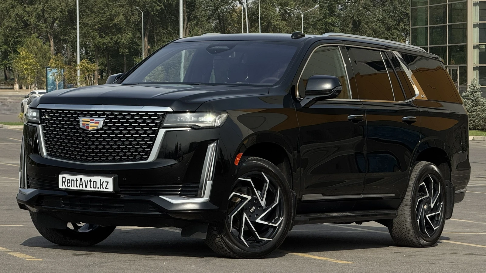 Чёрный Cadillac Escalade на городской улице, популярный для разных маршрутов по городу