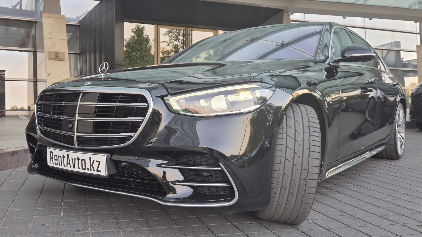 Mercedes-Benz S-Class 223 в чёрном цвете стоит у тротуара делового квартала Астаны, седан берут в аренду с профессиональным водителем для приёма делегаций