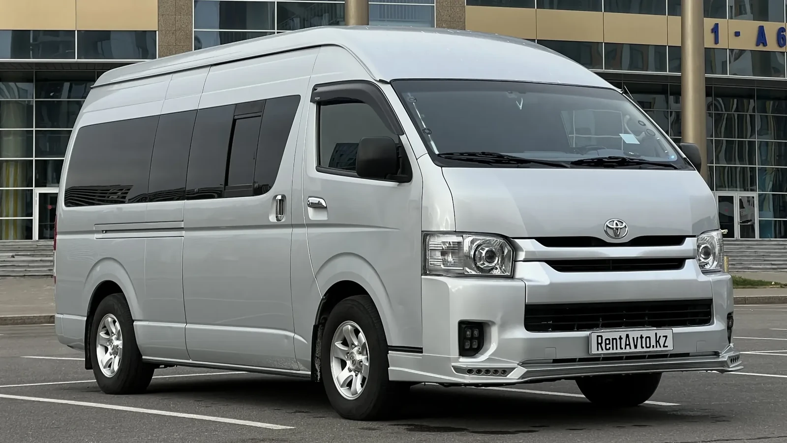 Toyota Hiace на 12 мест в светлом ракурсе возле зданий Астаны