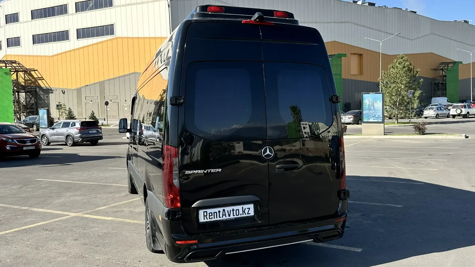 Задний ракурс чёрного Sprinter на 16 мест на стоянке автопарка в Астане